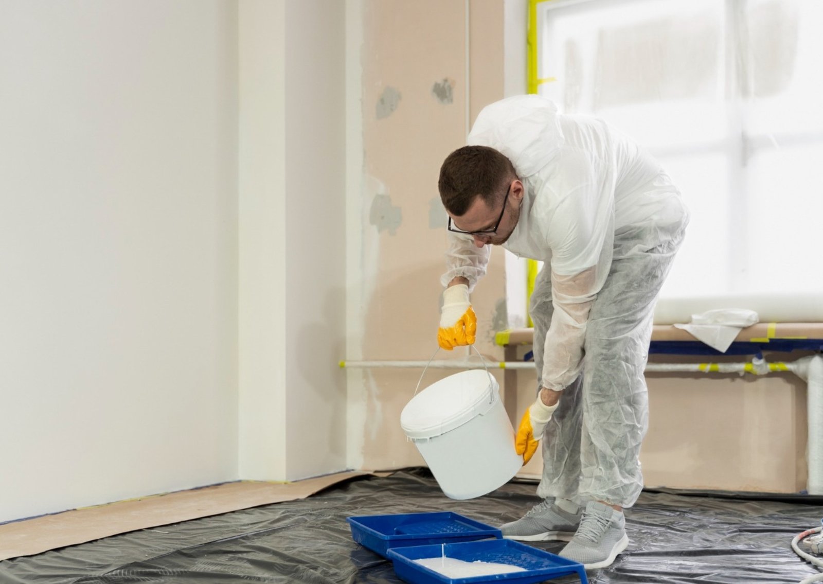 Professional painter applying fresh white paint on interior walls in Ontario residential home by BLX Design Renovation Construction